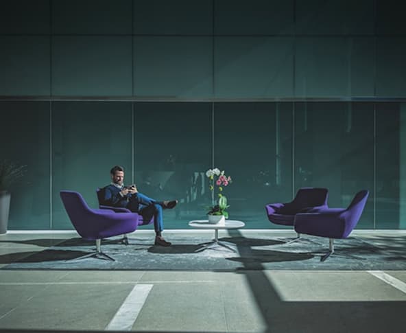 Homem sentado em uma poltrona mexendo no celular.